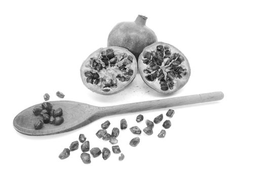Whole pomegranate and two cut halves with some seeds removed with a wooden spoon, isolated on a white background