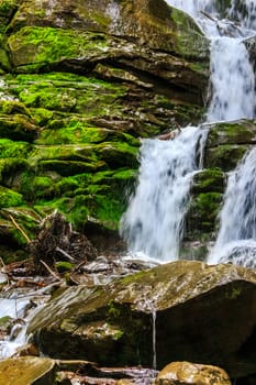 rugged mountain stream with large cascades. Wet large rocks covered with moss.