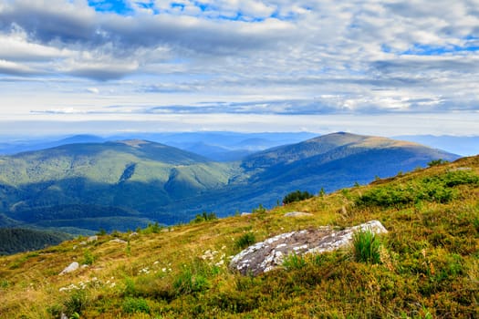 panorama of a mountain range and a large rock on the hillside