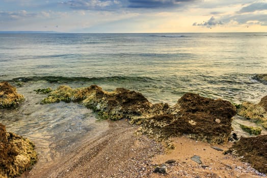 wave rolls onto the rocks on the sandy sea beach