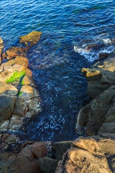 blue sea beating against the coastal jagged cliffs