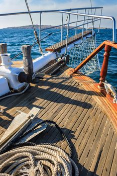 stem deck of a ship, with anchor and rope, walking on the sea towards the island on a sunny day