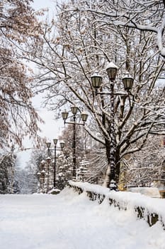 part of the pedestrian road going up with the curb and lanterns covered with snow