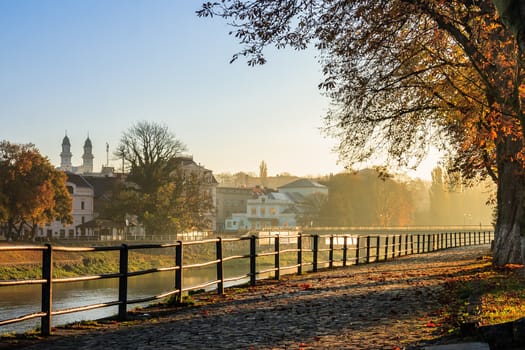 embankment of the old town strewn with foliage and filled with light on autumn morning