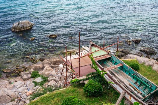 old broken boat on the rocky shore waiting repair for a long time