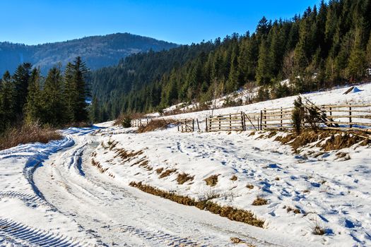 fence by the road to forest in the mountains on a fine winter day