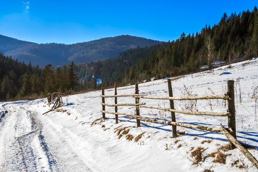 fence on the snow-covered mountain slope near the forest in winter