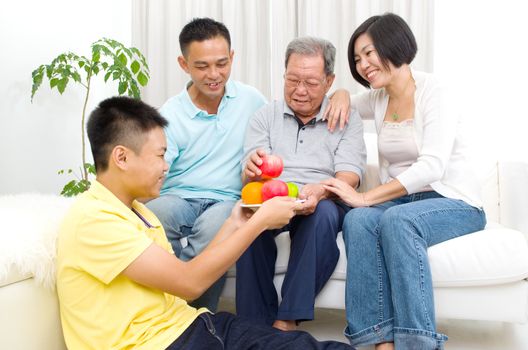 Happy asian family eating healthy fruit.