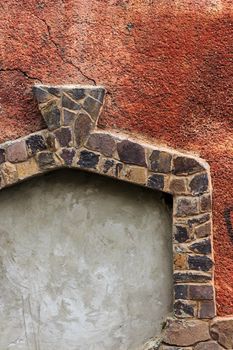 immured doorway with shaped frame of stone on the red cracked plaster texture