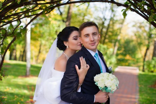 The bride tenderly embraced the groom standing under the green arch