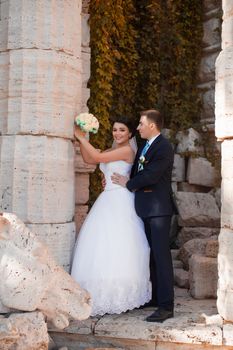 The groom tenderly embraced the happy bride standing at the column