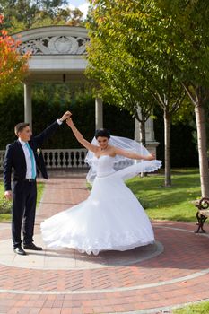 A happy bride swirls for the groom in the summer park on the mall