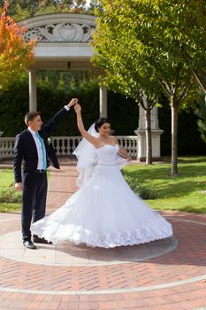 A happy bride swirls for the groom in the summer park on the mall