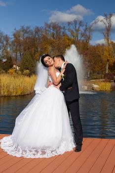 The groom tenderly kisses the happy bride in the neck standing on the pier