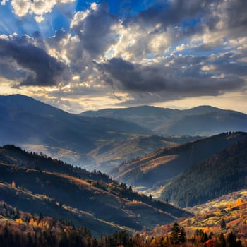 autumn landscape. forest on a hillside covered with red and yellow leaves. over the mountains against blue sky clouds