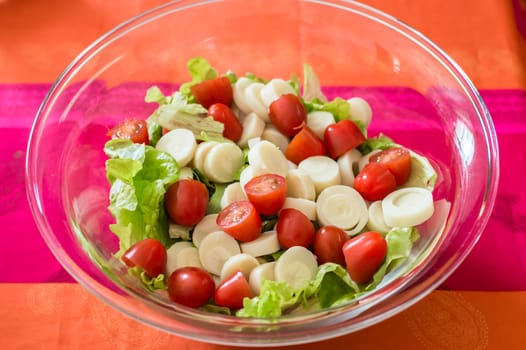 Close up salad with cherry tomatoes and lettuce in a glass bowl on the table