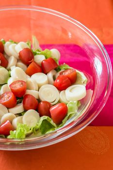Close up salad with cherry tomatoes and lettuce in a glass bowl on the table
