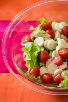 Close up salad with cherry tomatoes and lettuce in a glass bowl on the table
