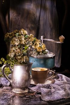 Flowers, cup of coffee and old coffee mill on a vintage background