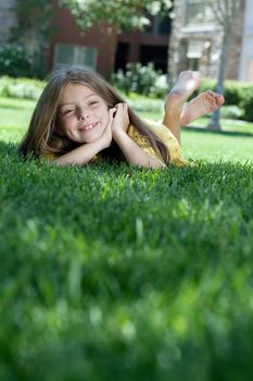 portrait of little girl laying on the grass in summer environment