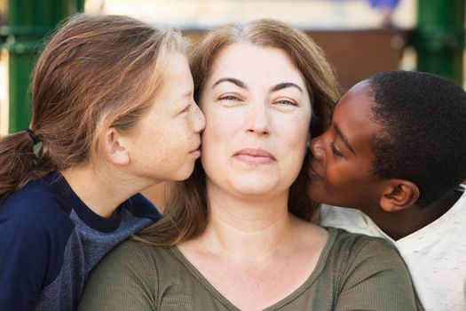 Happy mother being kissed on both sides of face by sons