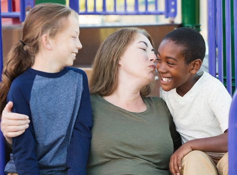 Single mother kissing her adopted son on cheek at park