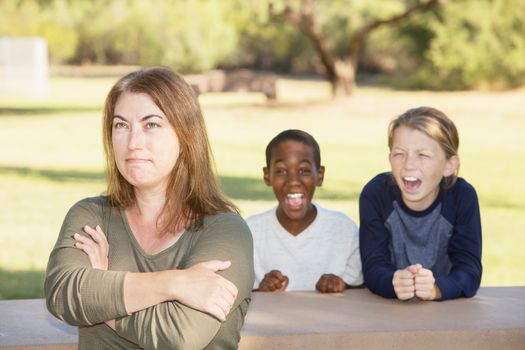 Frustrated mother sitting with loud sons demanding something outside