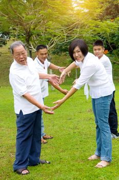 Portrait Of Multi-Generation Chinese Family showing love sign.