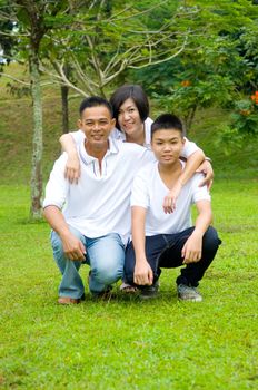 Young Chinese Family Relaxing In Park Together