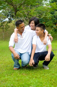 Young Chinese Family Relaxing In Park Together