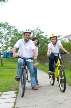 Asian Family On Cycle Ride In Countryside