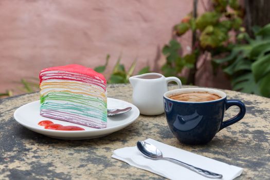 crape cake rainbow and hot espresso coffee in garden side home. crape cake with strawberry sauce