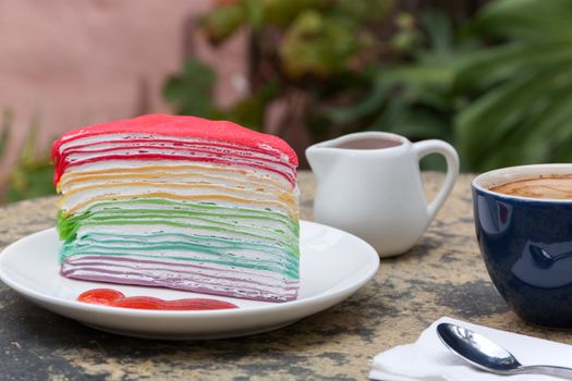 crape cake rainbow and hot espresso coffee in garden side home. crape cake with strawberry sauce