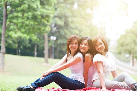 Group of Asian females having fun at outdoor park, sisters or girlfriends, friendship concept, sun flare background.