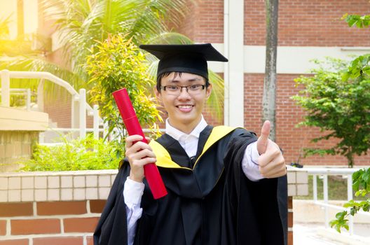 Cheerful asian university graduate giving thumb up sign