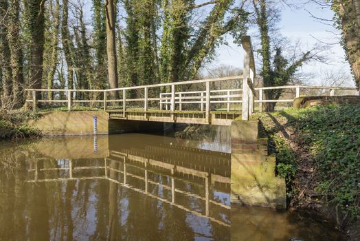 Old rundown wooden bridge over the brook the Boven-Slinge near Winterswijk in the Achterhoek in the early spring in the Netherlands
