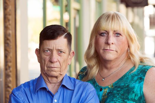 Serious looking mature transgender couple standing together outside in urban setting