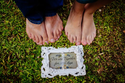 couple's feet together on green grass close up