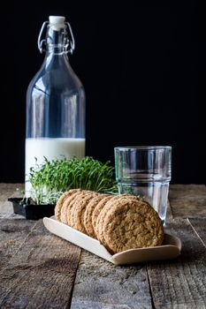 Milk and chocolate cookies on an old wooden table, black background