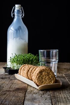 Milk and chocolate cookies on an old wooden table, black background