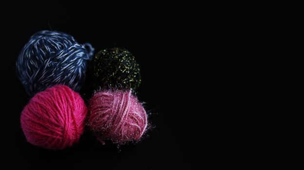 Four skeins of knitting yarn isolated on black background