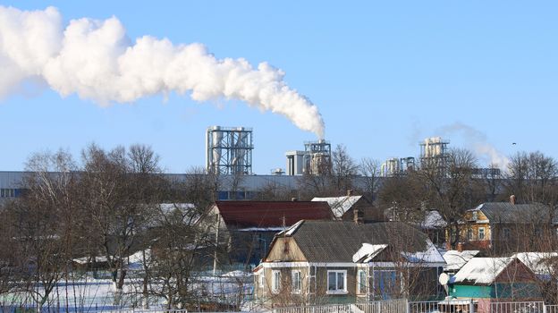 White smoke from the chimney on blue sky background. Ecology industry environment pollution city and village