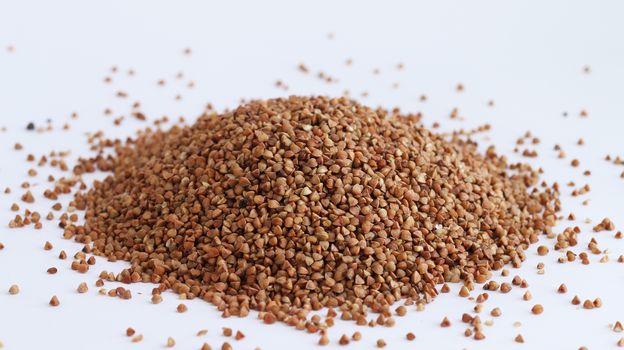 Pile of buckwheat on white background. Agriculture food raw seed. Closeup macro photo