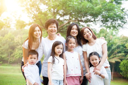 Group of happy Asian multi generations family portrait, grandparent, parent and children, outdoor nature park in morning with sun flare.