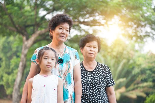Portrait of multi generations Asian family at nature park. Grandmother and grandchild outdoor fun. Morning sun flare background.