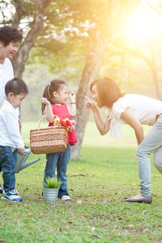 Candid portrait of happy multi generations Asian family at nature park. Grandmother, mother and children outdoor fun. Morning sun flare background.