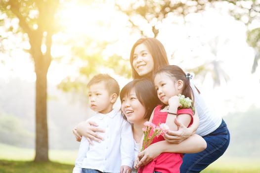 Asian family at park, parents and children, outdoor in morning with sun flare.