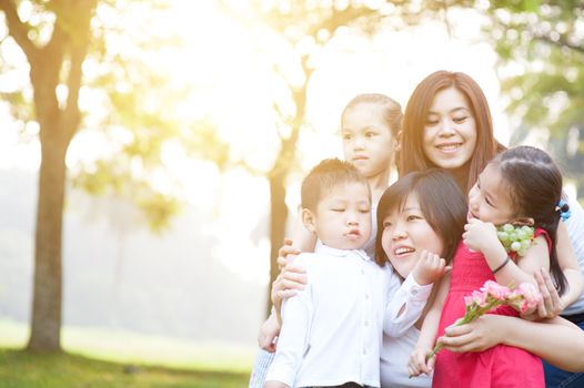 Asian family at nature park, parents and children, outdoor in morning with sun flare.