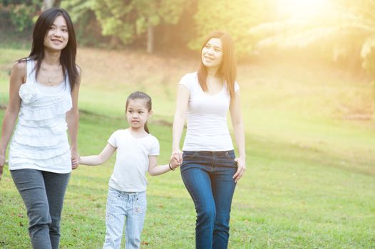 Asian family walking at nature park, morning outdoor with sun flare.