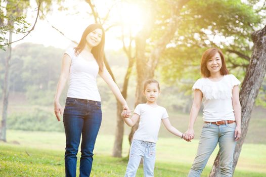 Asian family walking at nature park, parents and child, outdoor in morning with sun flare.